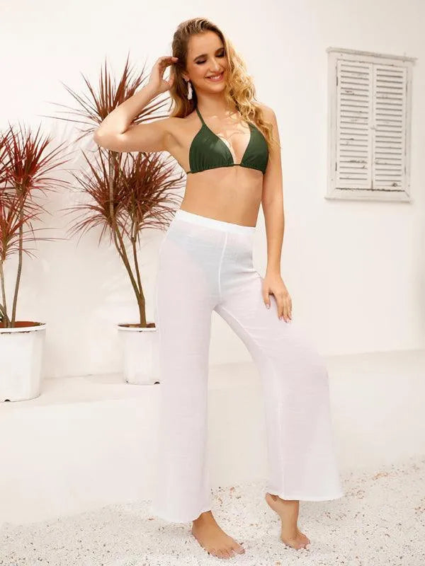 Woman in white sheer wide-leg beach pants and a green bikini top fashion image